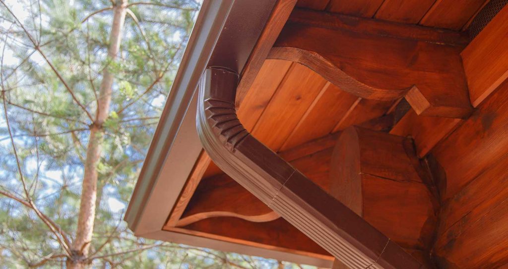 Aluminum downspout elbows carrying water away from the wall of a home