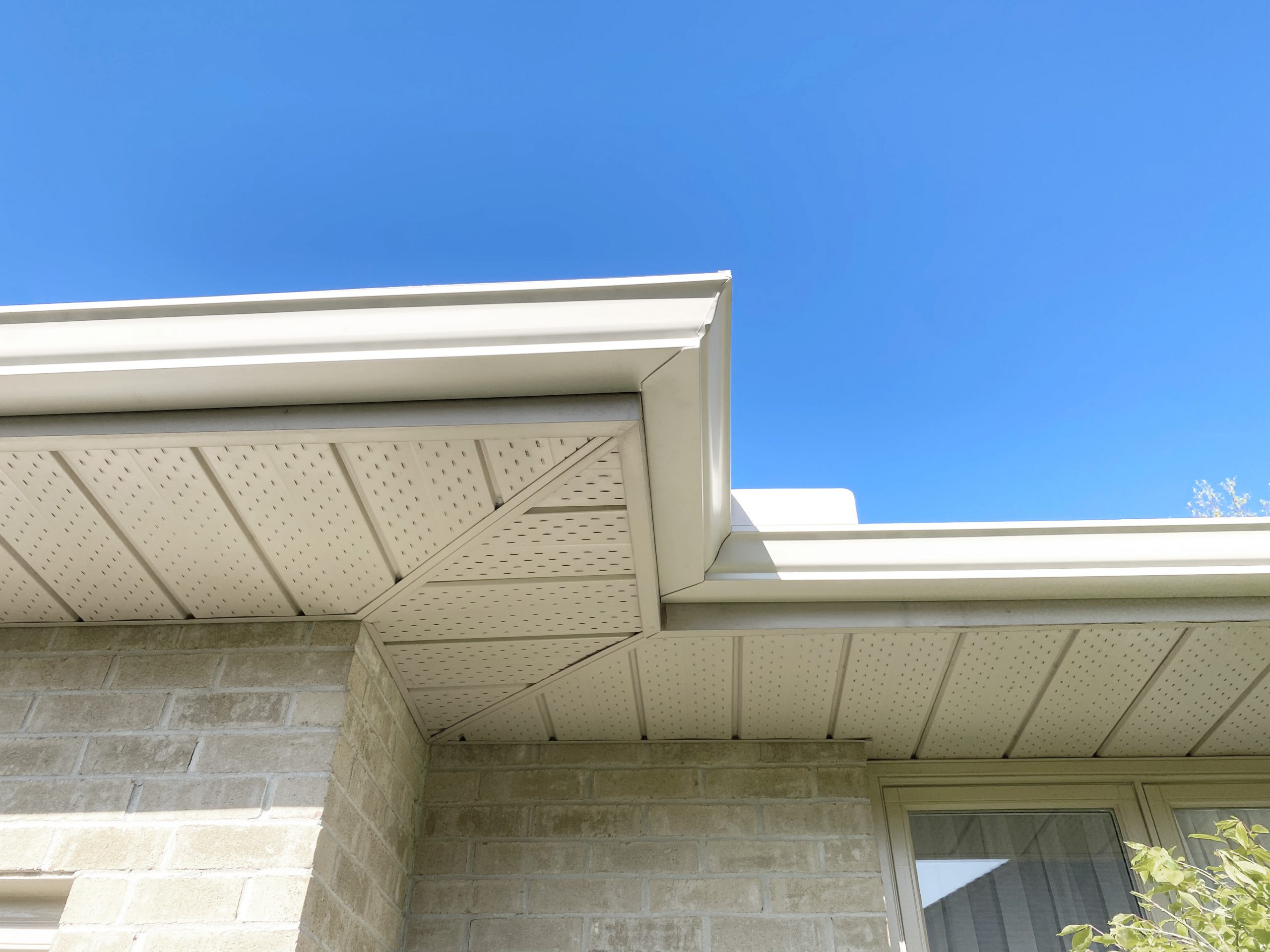 Seamless gutters installed professionally looking from below against blue sky