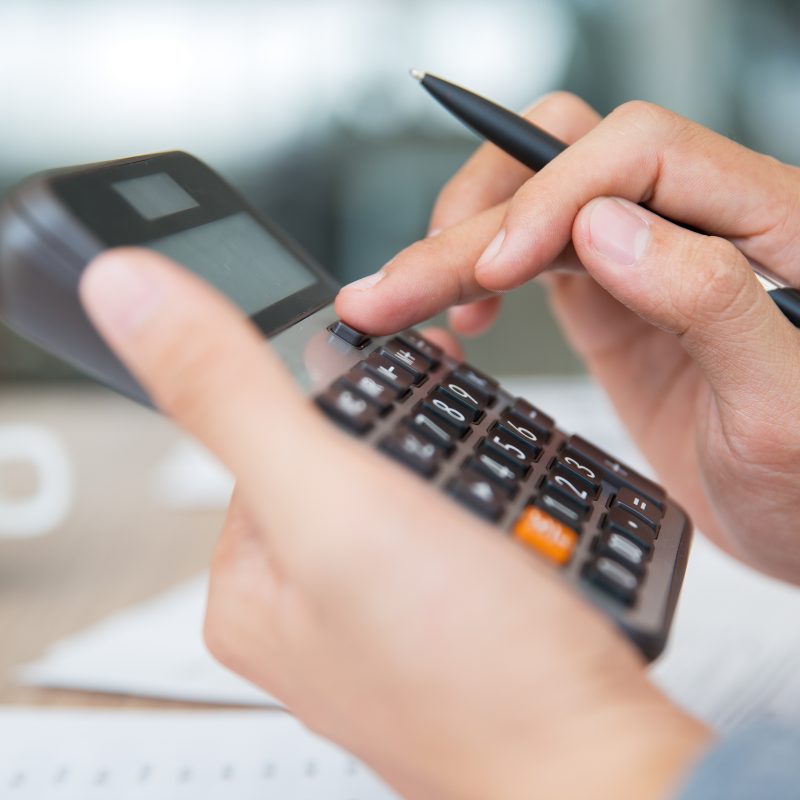 Close-up of male hands using calculator. holding pen when pushing button on calculator determining cost of gutters