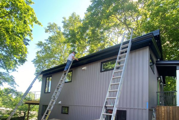 person on ladder working on new gutter installation