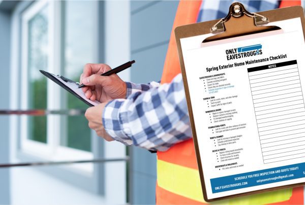 Person in orange vest holding clipboard is completing exterior home maintenance checklist
