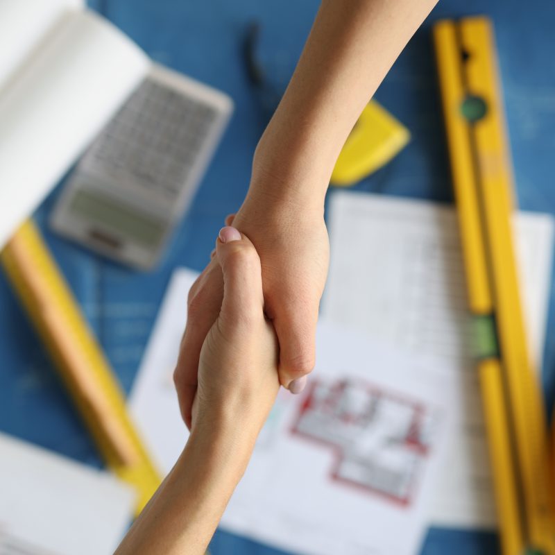 Handshake between contractor and client over documents for dream home exterior remodel