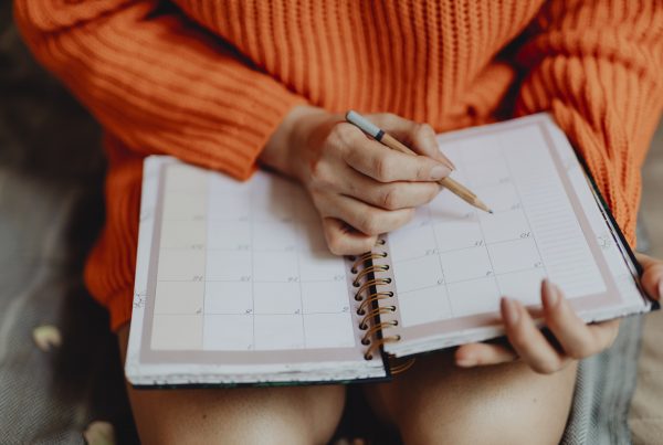Woman writing on her daily planner deciding best time to install new siding