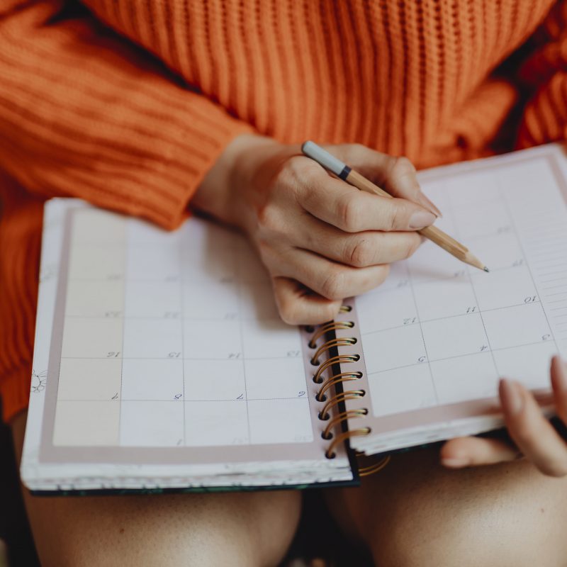 Woman writing on her daily planner deciding best time to install new siding